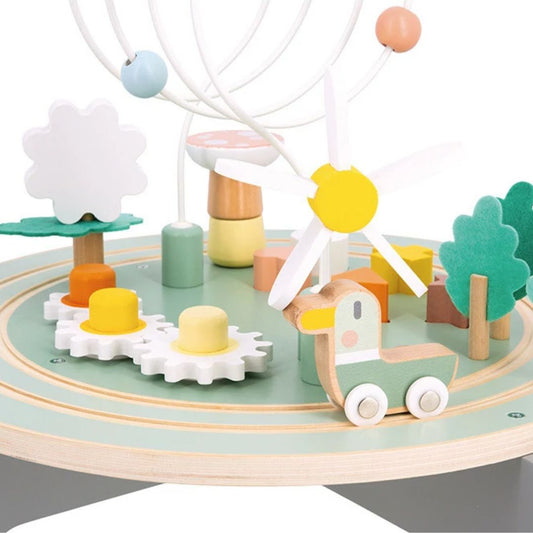 Wooden toy set with trees, cars, and a Ferris wheel on a circular Janod Activity table.