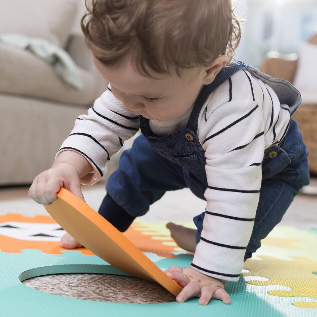 Child playing on a colorful mat with an orange pieace