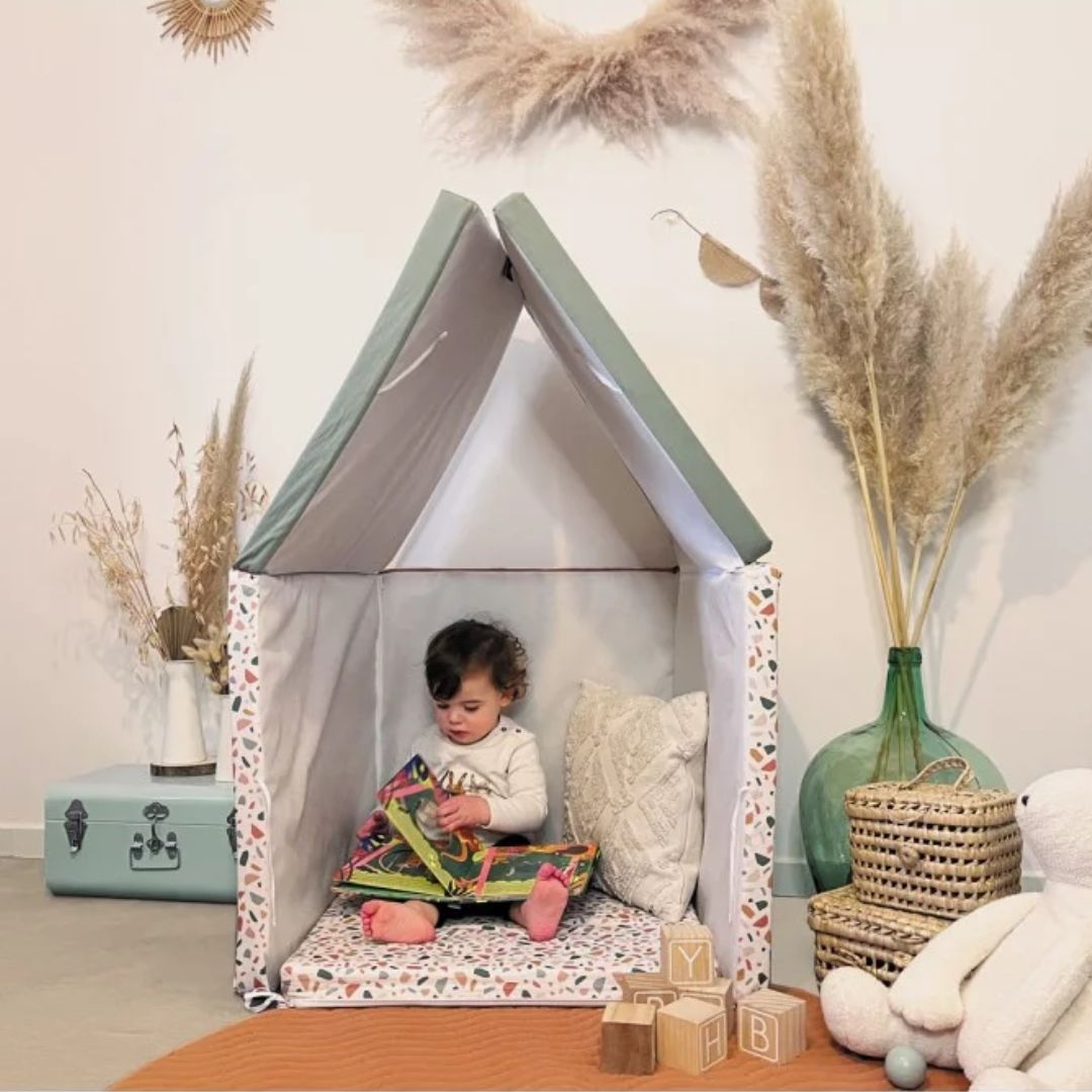 Child playing inside a play tent with decorative elements in the background