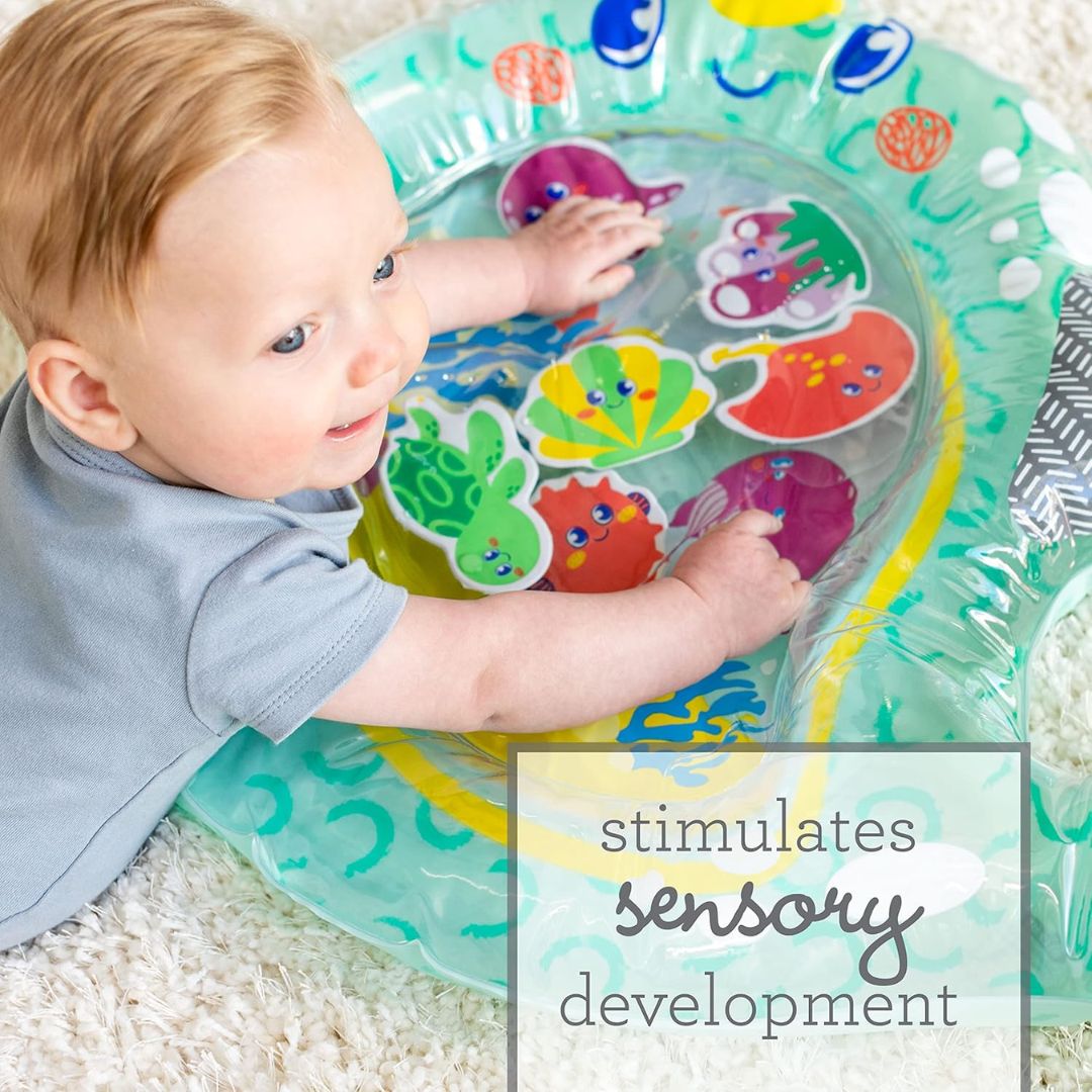 Baby playing with a colorful water toy on a carpeted floor.