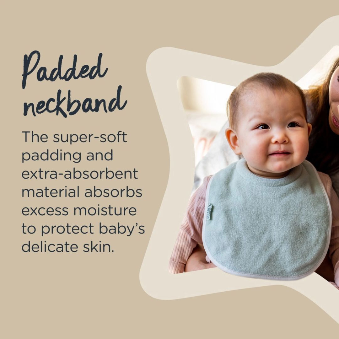 Baby wearing a light blue Tommee tippee bib with text about padded neckbands on a beige background