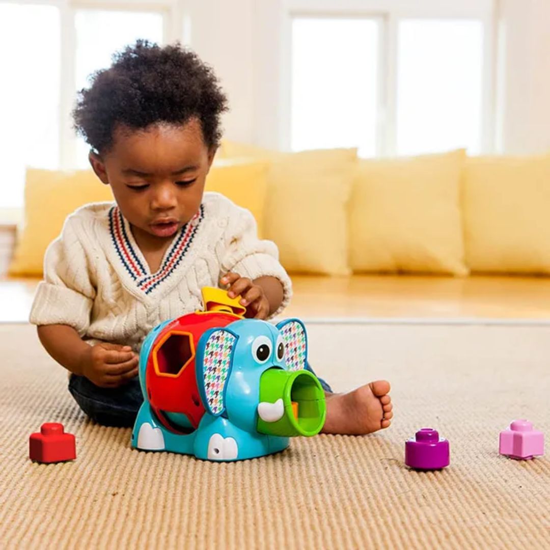 Child playing with a colorful toy elephant on a carpeted floor.