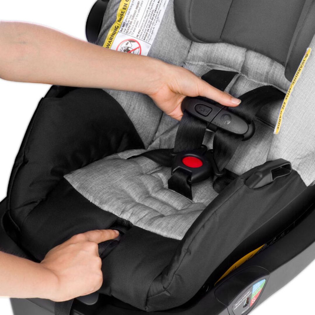 Person securing a child in an Evenflo car seat with straps.