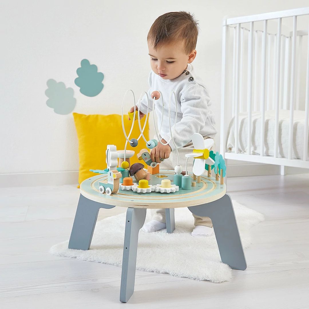 Child playing with a wooden toy set on a small Janod table in a nursery.