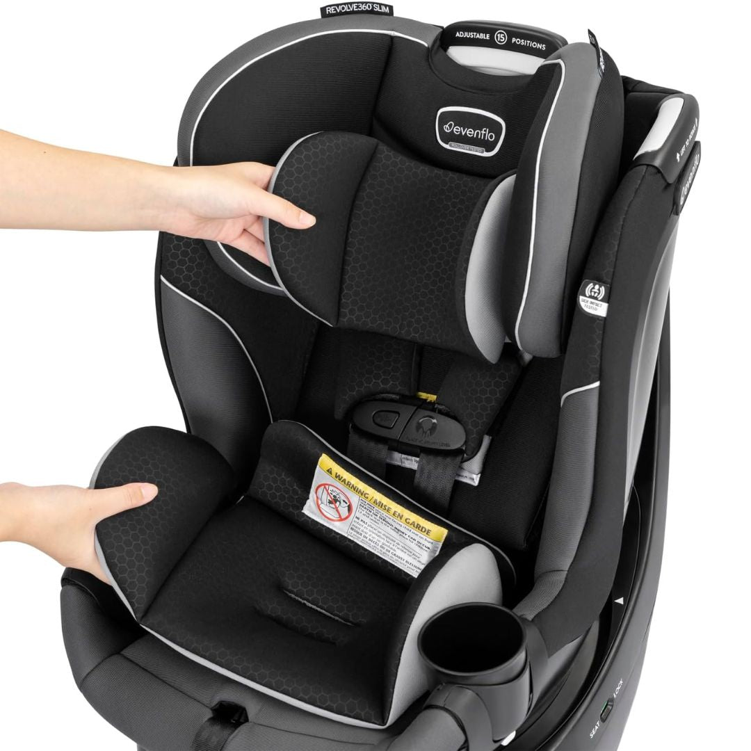 Evenflo Black and gray car seat with a hand adjusting it on a white background