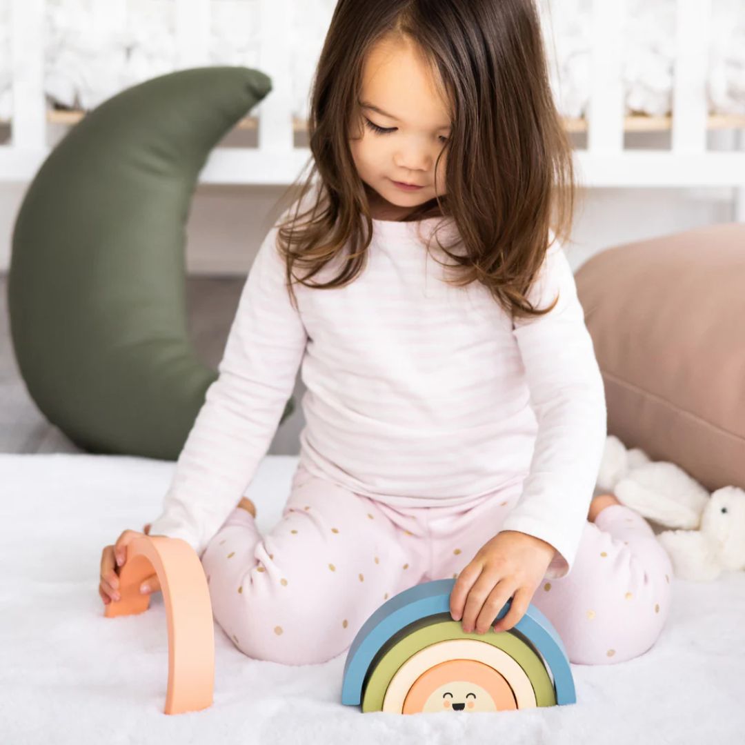 Child playing with colorful Pearhead wooden toys on a bed