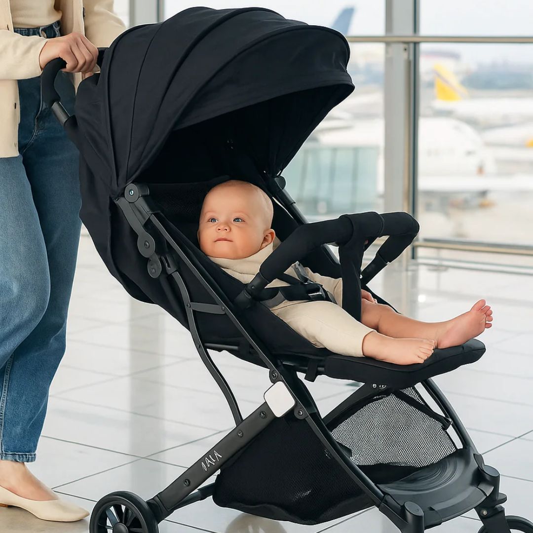 Baby in a Miila black stroller with a blurred airport background