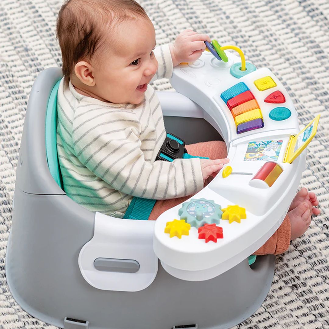 Baby playing with an Infantino colorful baby seat toy on a textured surface