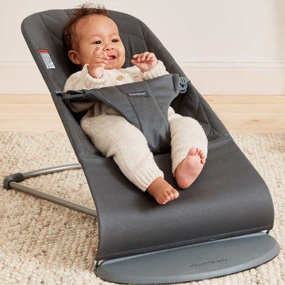 Baby in a gray BabyBjorn Bouncer seat on a carpeted floor