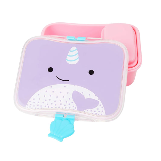 A pastel pink and lavender Skip Hop snack box with a cute narwhal face printed on the lid, shown with a small blue clamshell clip on a white background.