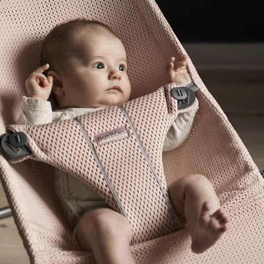 Baby in a pink baby bouncer looking around