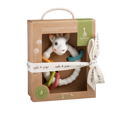 Sophie la Girafe Colo'rings teething ring in its natural rubber gift box packaging, tied with a cream ribbon printed with the Sophie la Girafe logo, labeled 3 months and up.