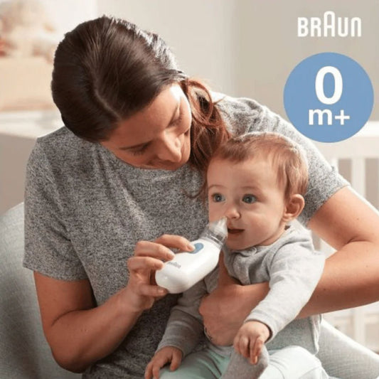 Woman holding a baby and using a Braun baby product in a home setting
