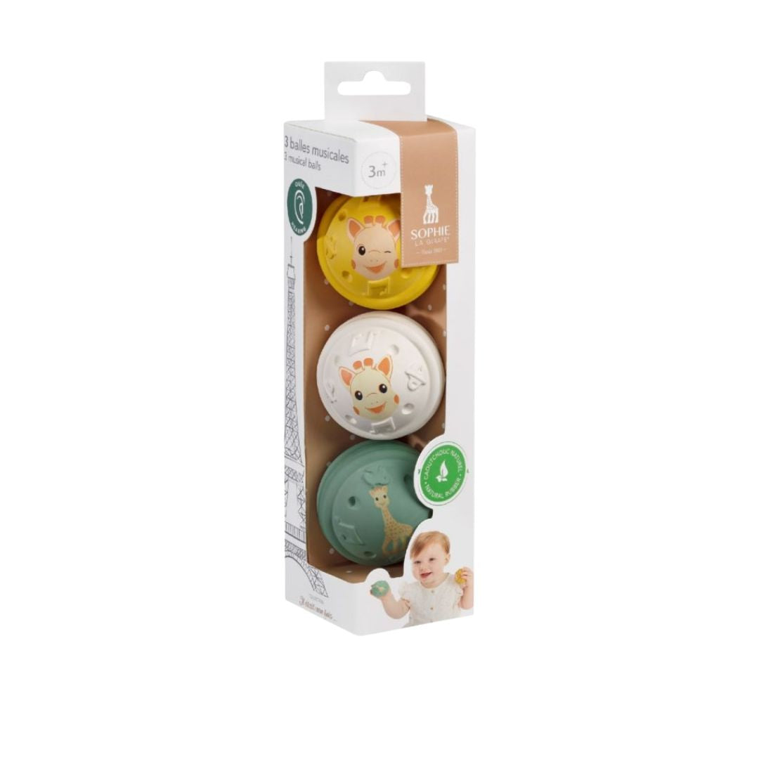 Sophie la Girafe set of 3 musical balls in yellow, white, and green, shown in retail packaging labeled 3 months and up, made from natural rubber.