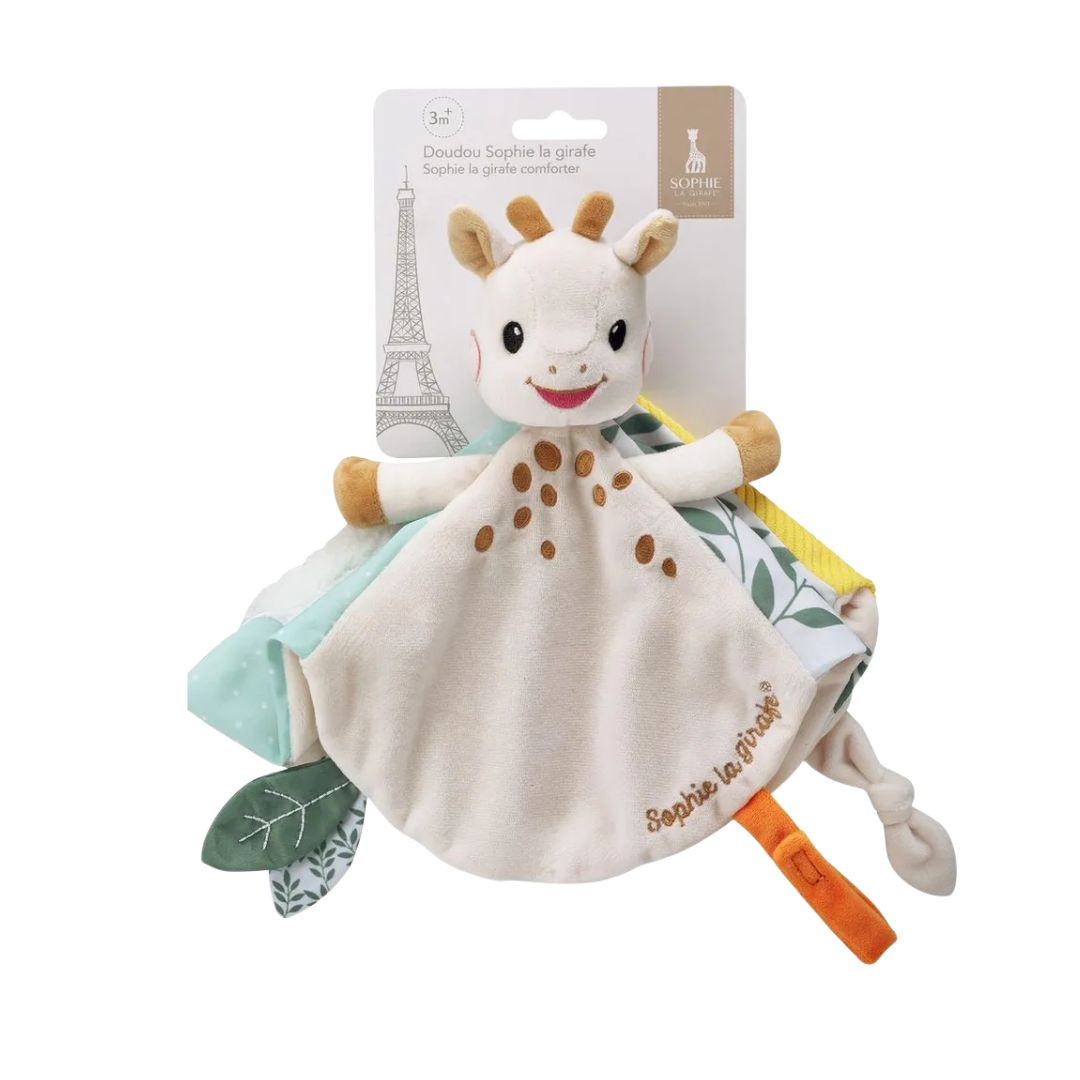 Sophie la Girafe plush comforter in retail packaging, a soft blanket toy with a giraffe head and patterned corners in mint, yellow, and leaf print, labeled 3 months and up.