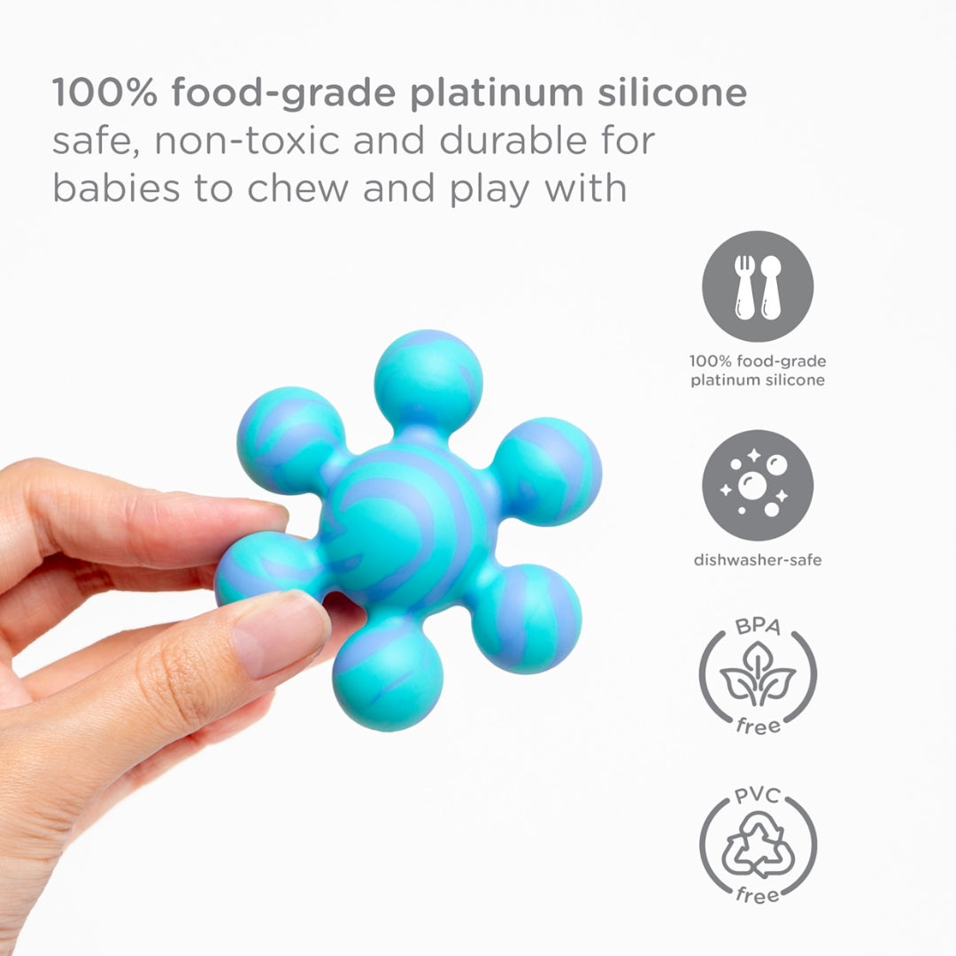Blue Ubbi silicone teether toy held by a hand with safety certification icons on a white background