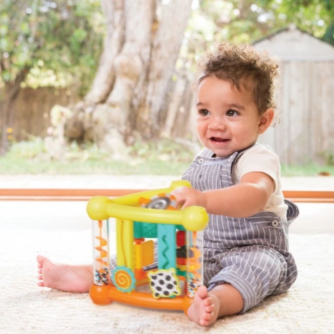 A baby playing with his Infantino triangle activity toy on a beige carpet