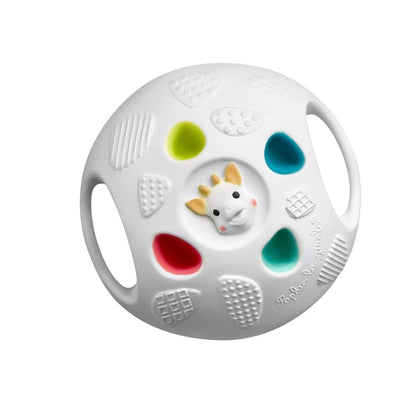 Sophie la Girafe Senso Ball, a white sensory ball with a small giraffe head in the center, surrounded by colorful textured panels in green, red, blue, and teal, and side handles for grip.