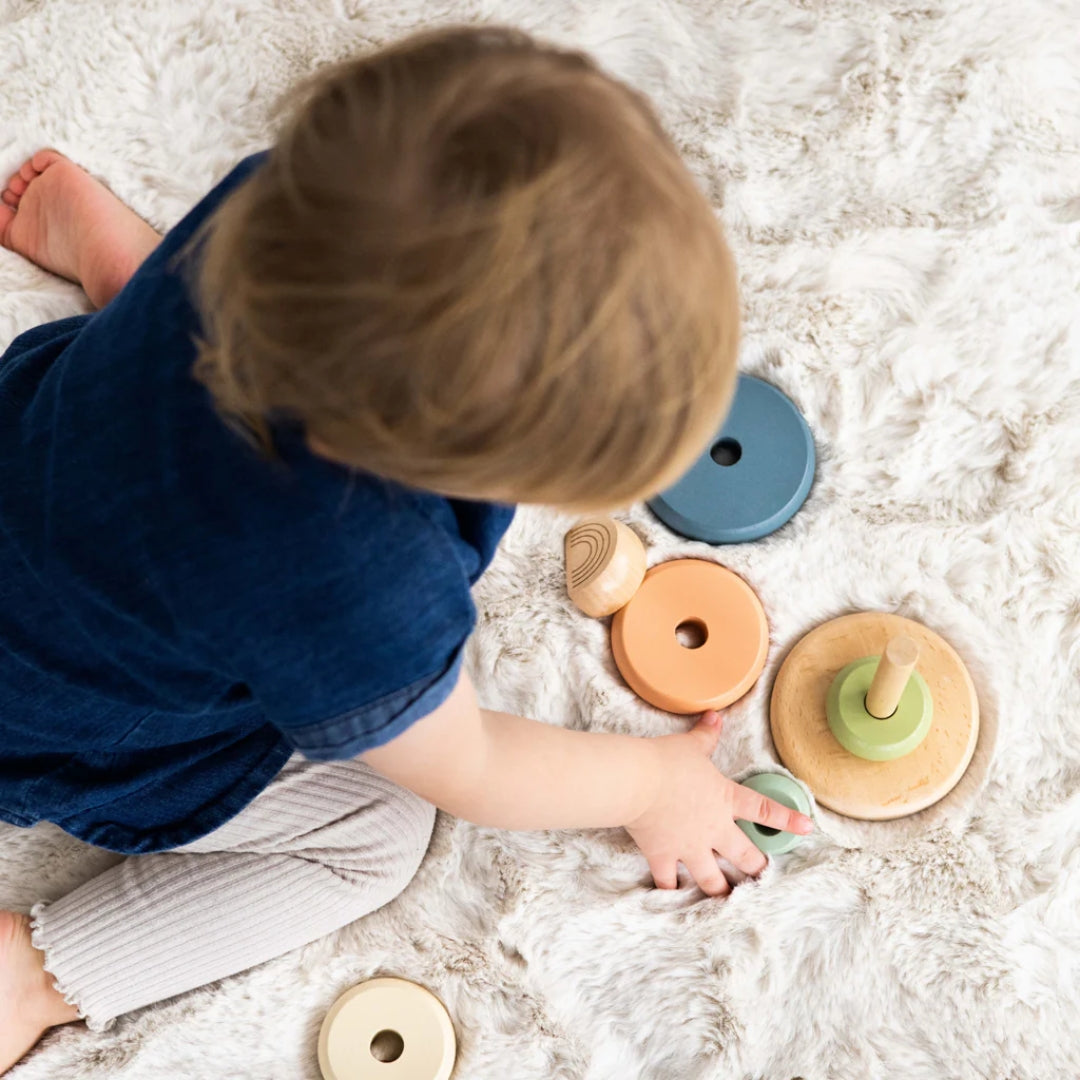 Child playing with Pearhead wooden toys on a soft surface