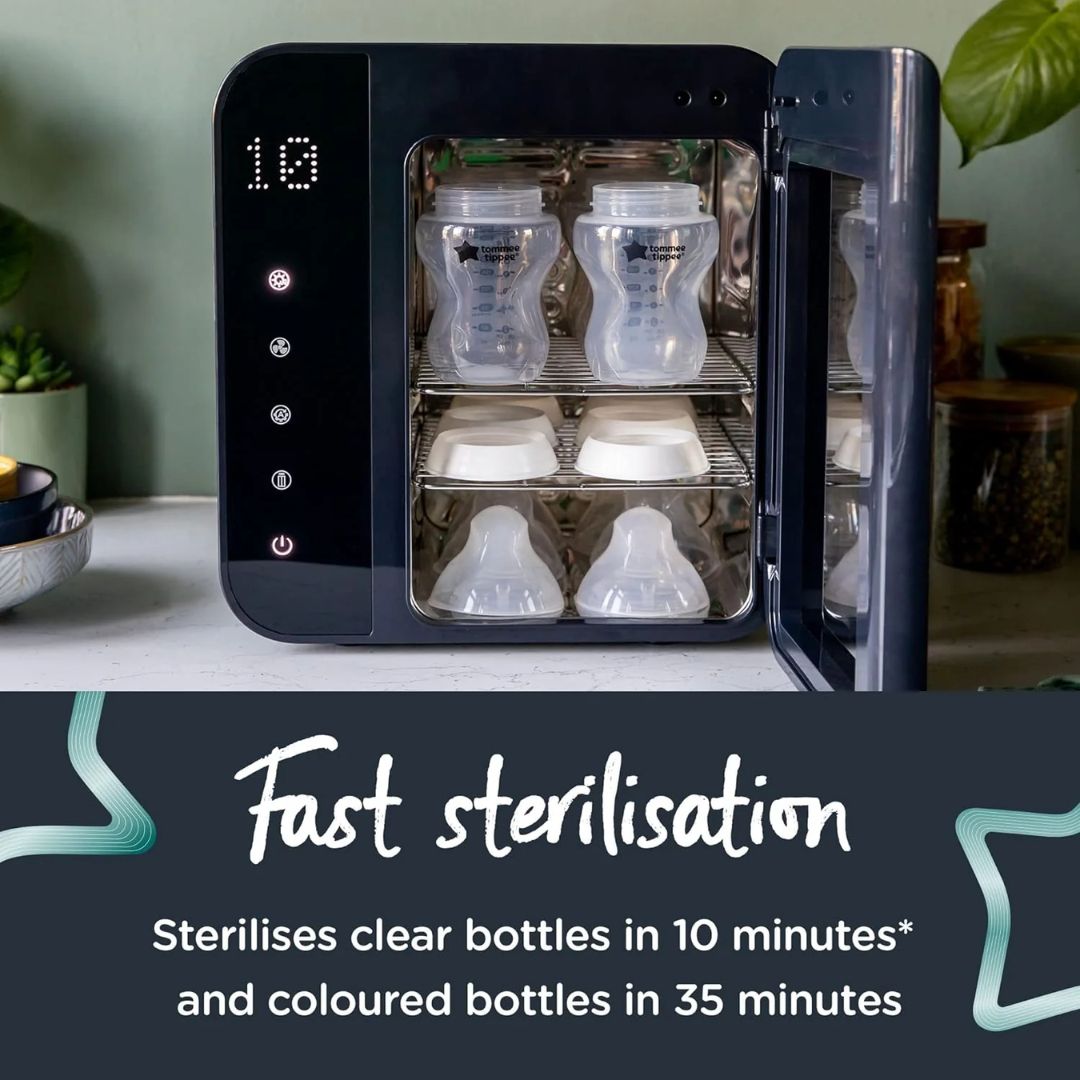 Tommee tippee Black sterilizer with clear and colored bottles inside, on a light surface with plants in the background.