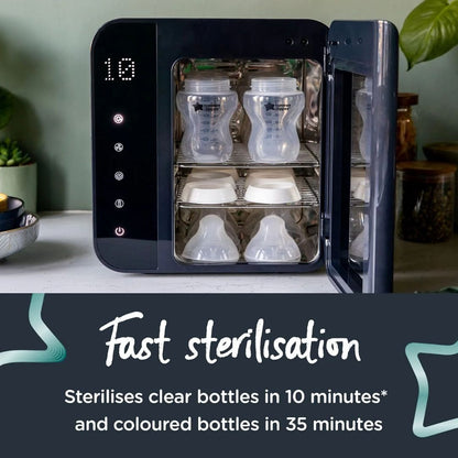 Tommee tippee Black sterilizer with clear and colored bottles inside, on a light surface with plants in the background.