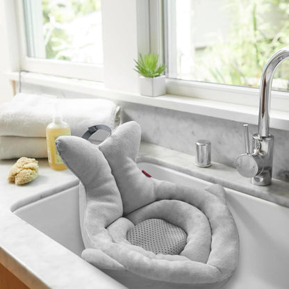 Gray bath pillow on a kitchen sink with a window in the background