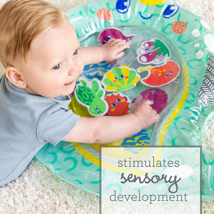Baby playing with a colorful water toy on a carpeted floor.