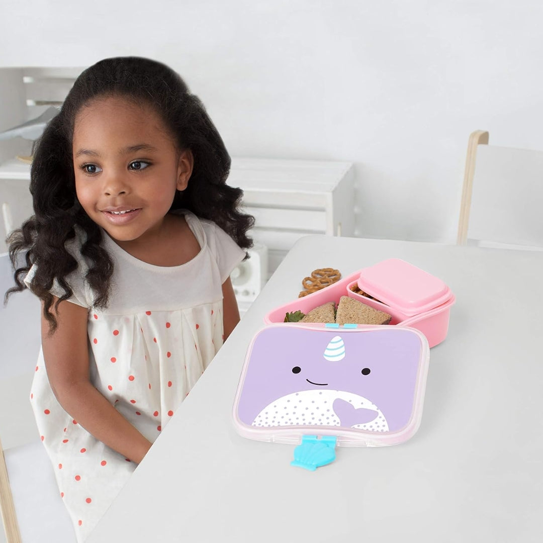 Child with Skip Hop Narwhal Lunch Box on a white surface