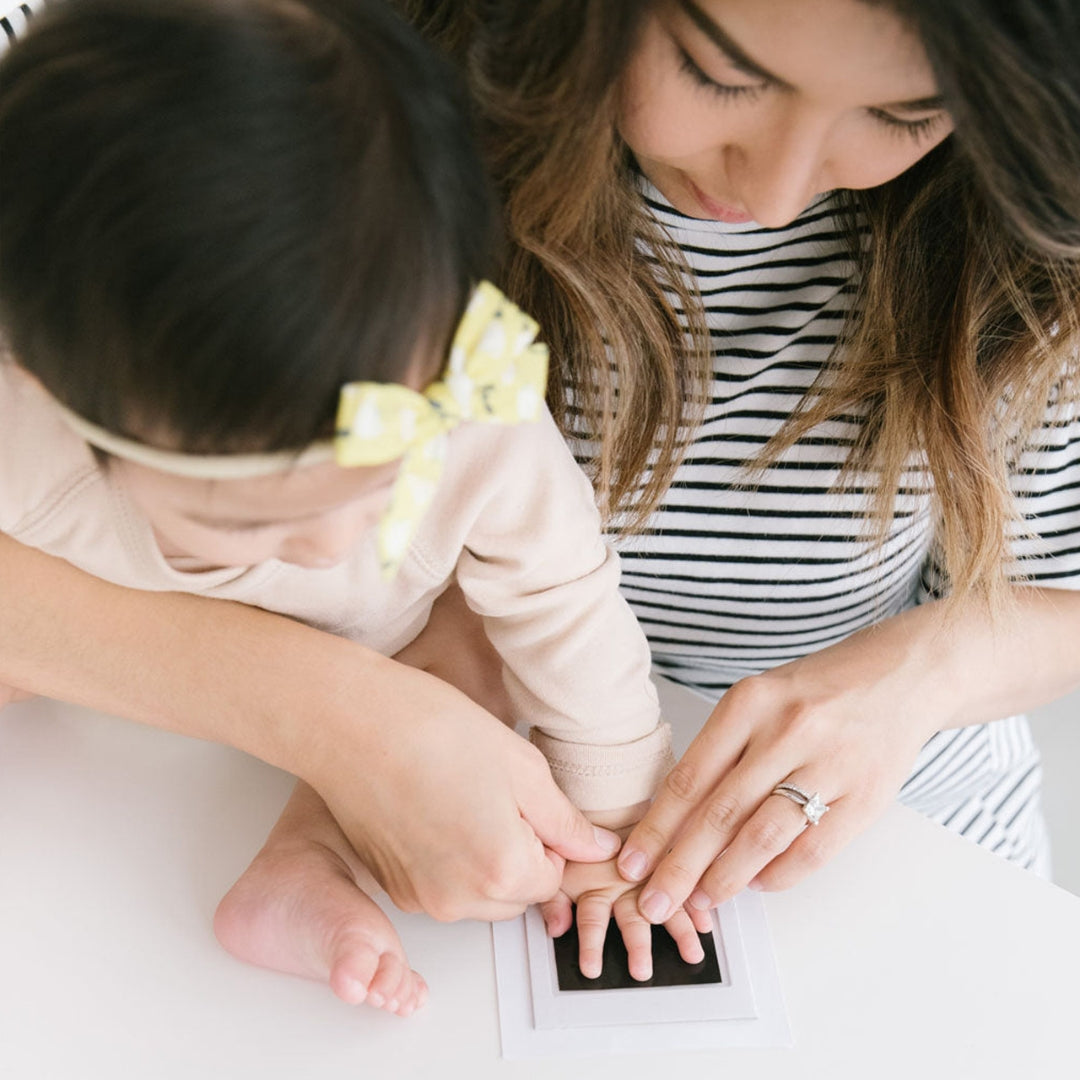 Woman and child sitting together, looking at a Pearhead handprint.