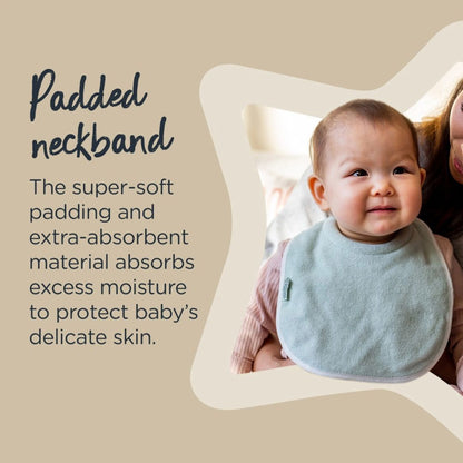 Baby wearing a light blue Tommee tippee bib with text about padded neckbands on a beige background