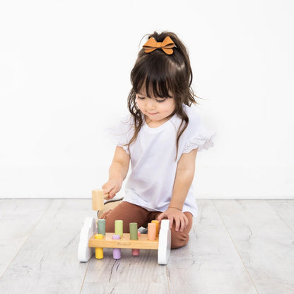Child playing with a Pearhead wooden toy on a light wooden floor.