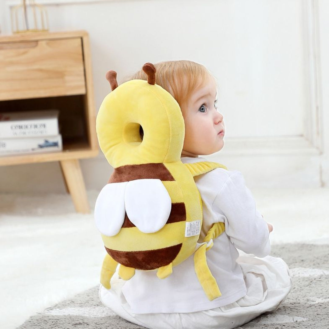 Child wearing a yellow and brown plush bee protector pillow indoors.