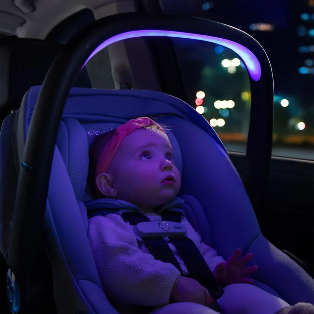 Baby in an Evenflo car seat with purple lighting at night