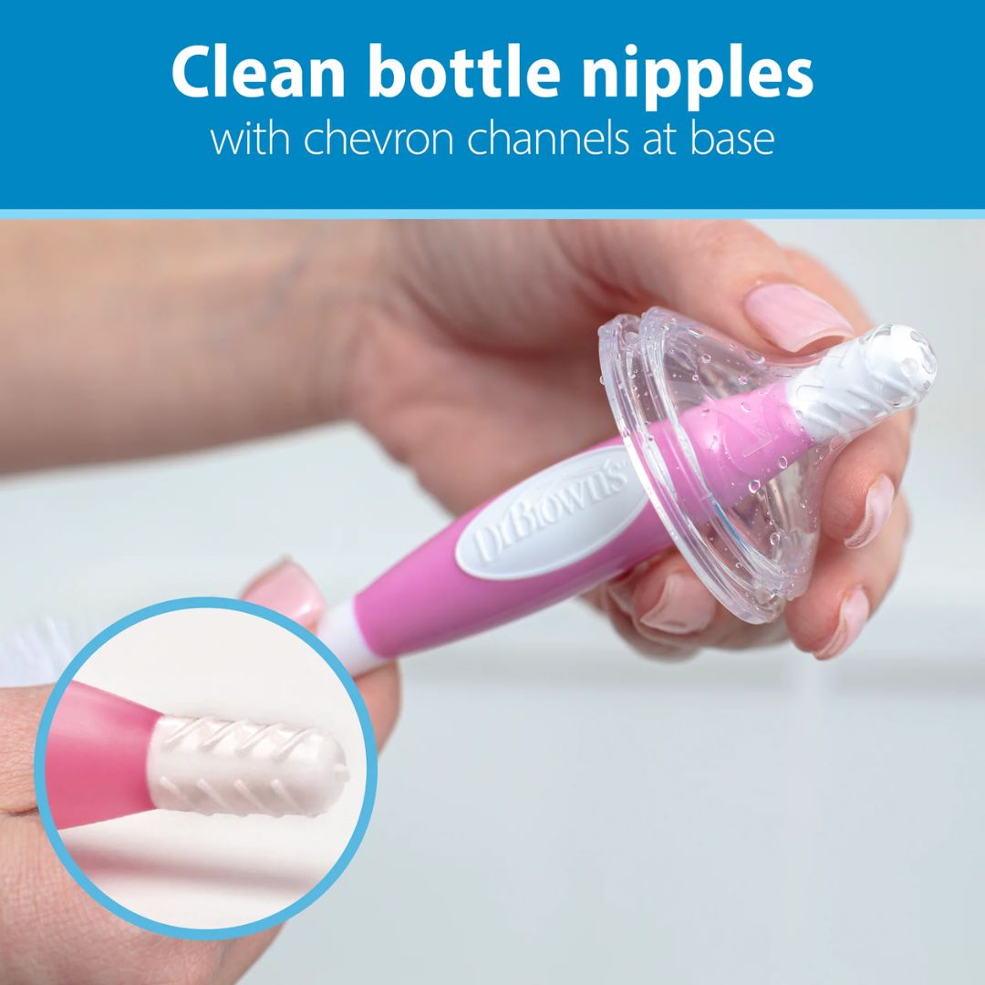Pink and white bottle nipple cleaner with chevron channels at base, held by a hand.