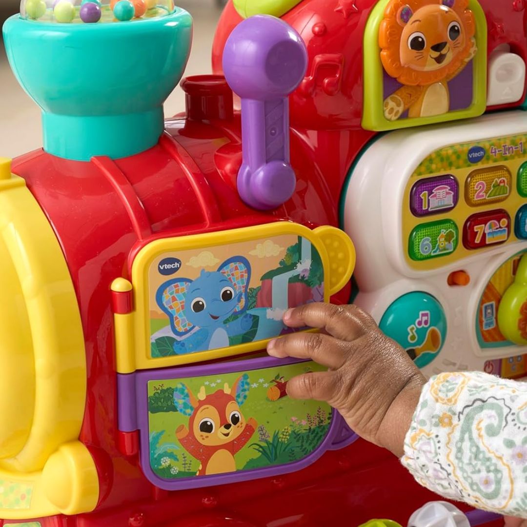 Colorful Vtech toy train with interactive elements, featuring a hand pressing a button.