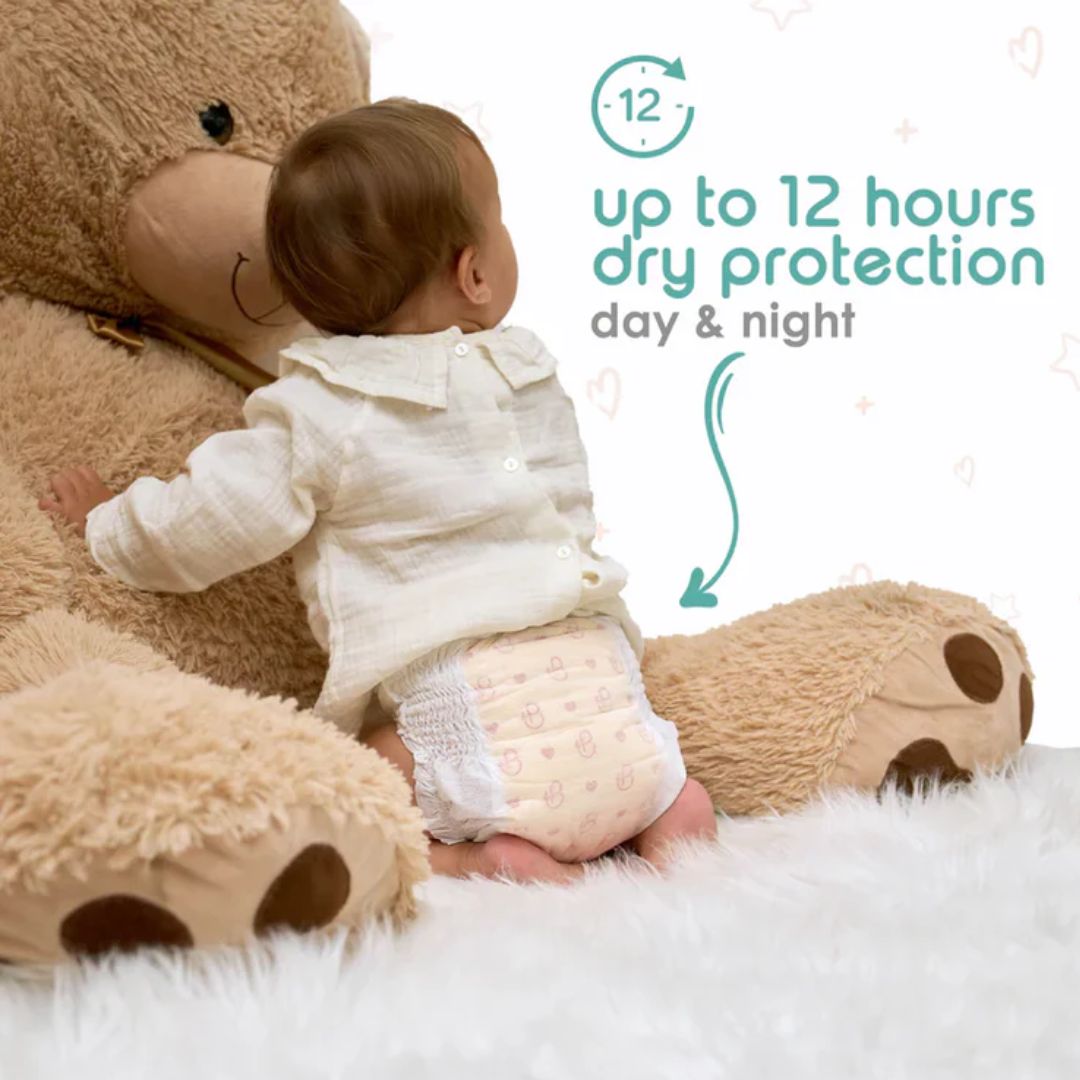 Baby in a diaper sitting next to a large teddy bear with text about dry protection.