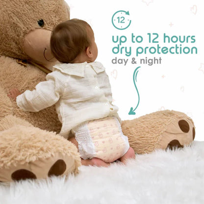Baby in a diaper sitting next to a large teddy bear with text about dry protection.
