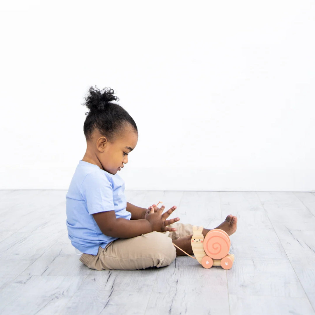 Child playing with a Pearhead toy on a white floor