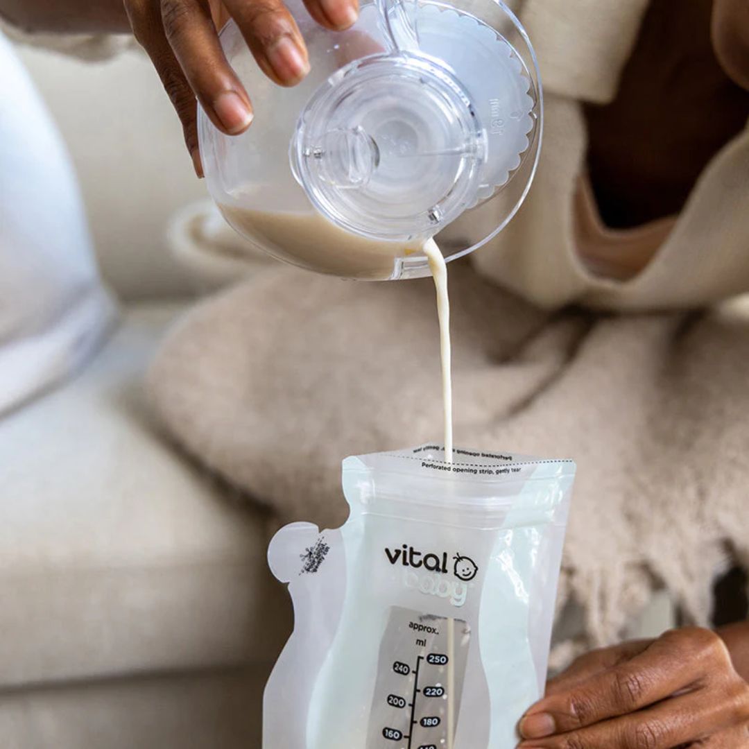 Person pouring milk from a container into a 'vital' baby bag.