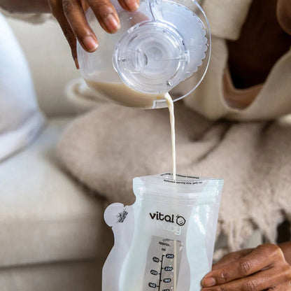 Person pouring milk from a container into a 'vital' baby bag.