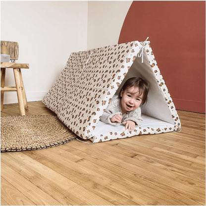 Child playing inside a candide patterned tent on a wooden floor.