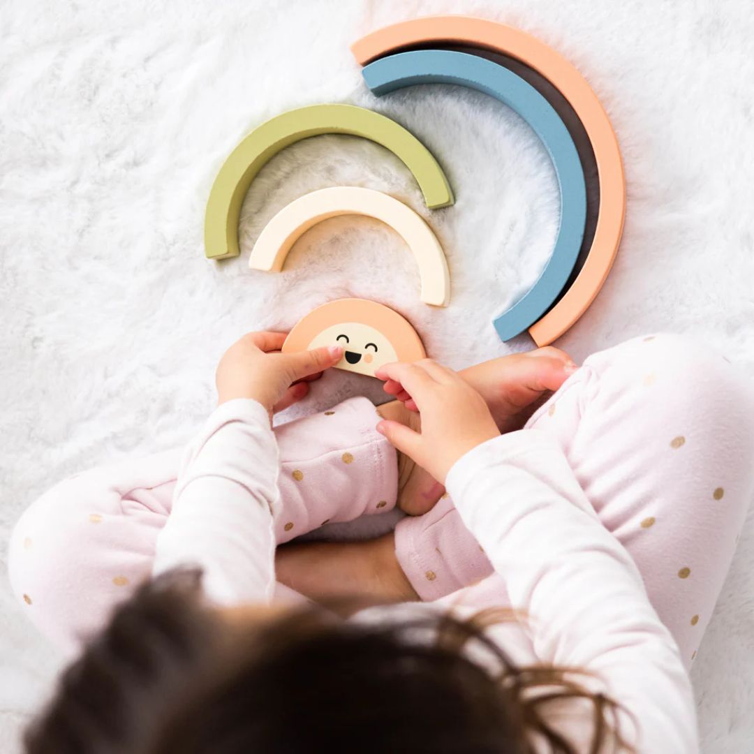 Child playing with colorful Pearhead wooden toys on a soft surface