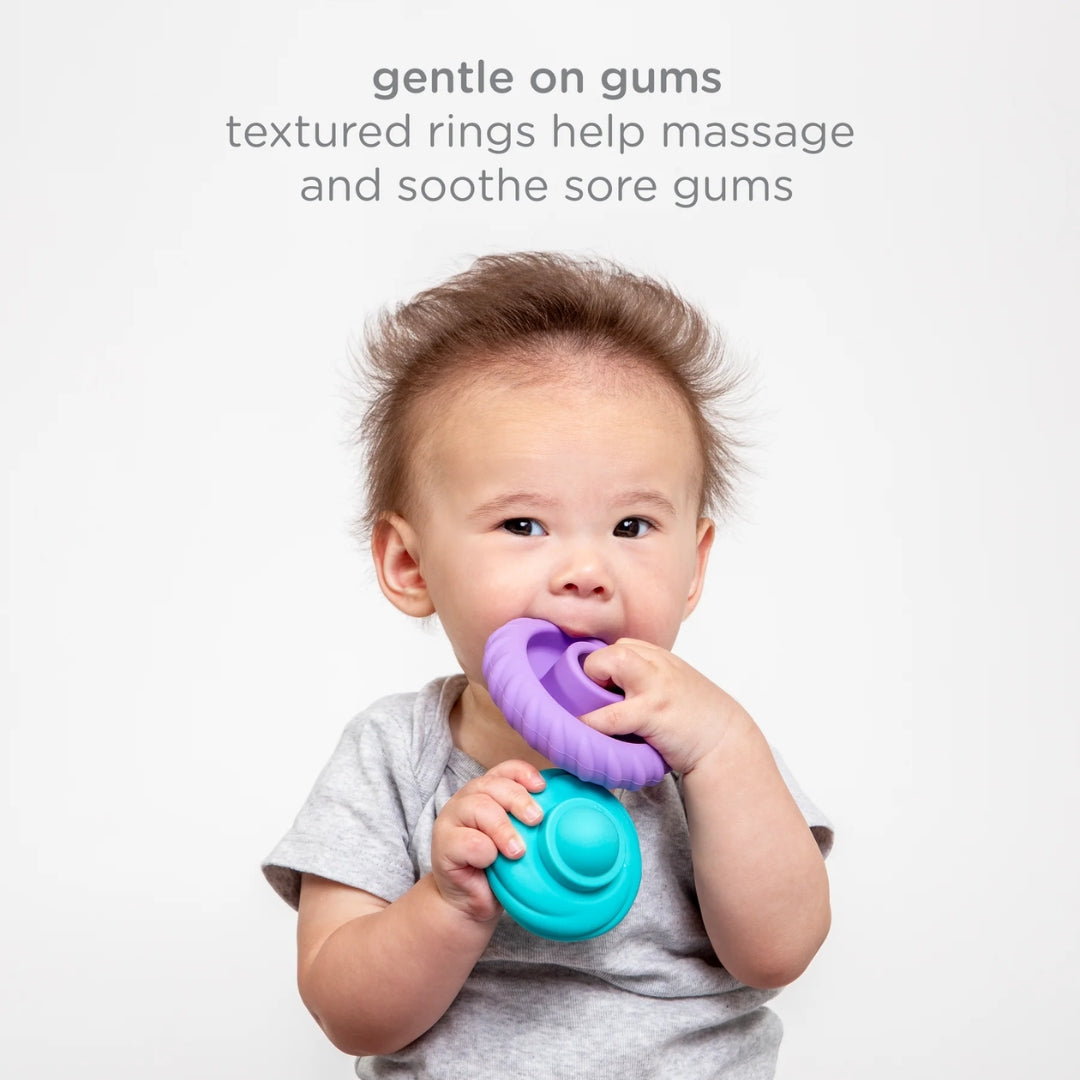 Baby holding a purple and blue teething ring with text about its benefits on a light gray background