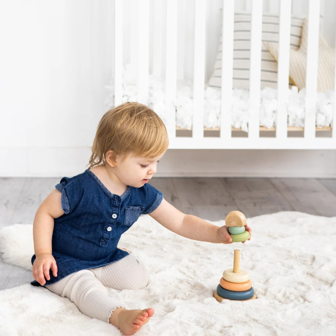 Child playing with a Pearhead wooden toy on a bed in a bright room