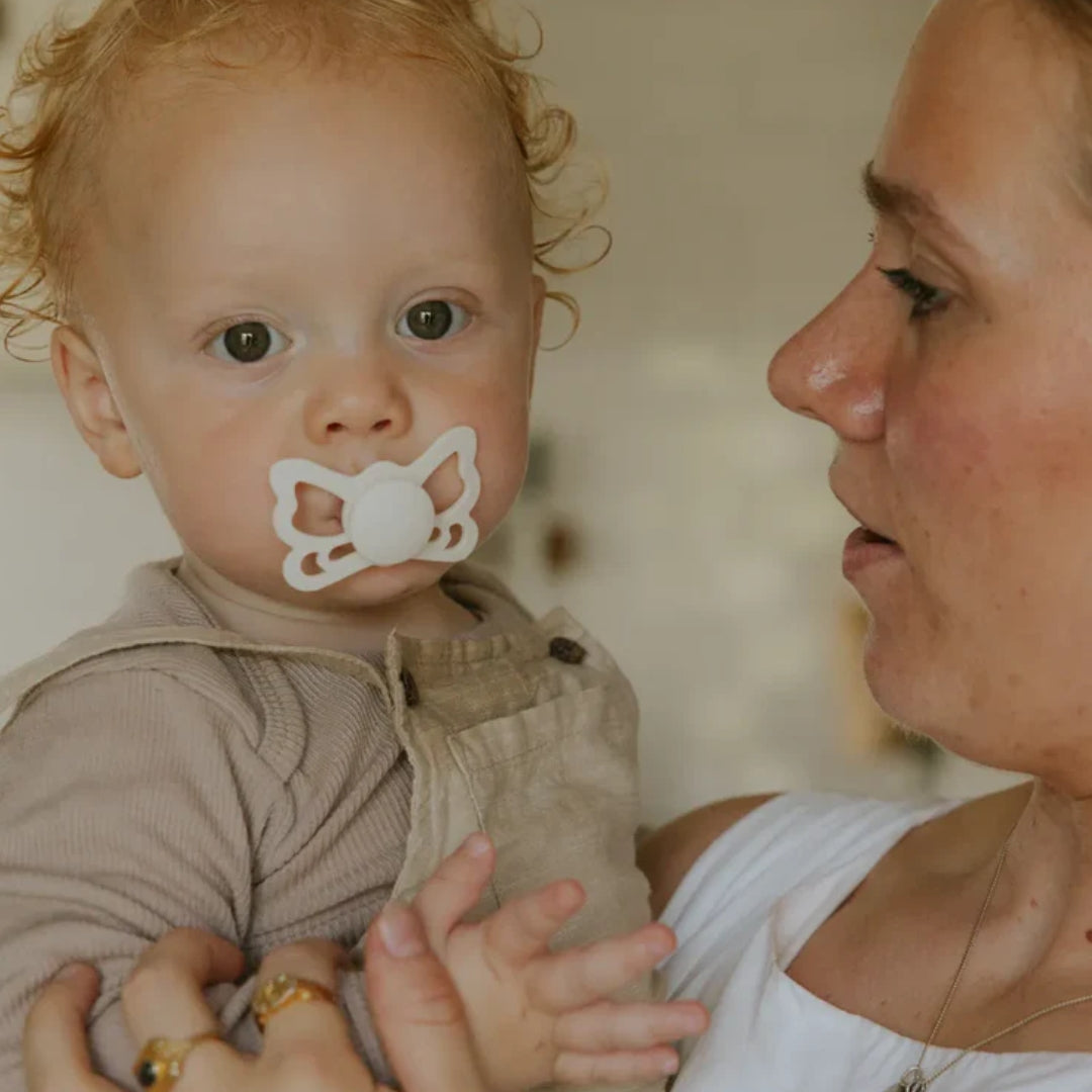 Baby with a Frigg butterfly pacifier held by a woman