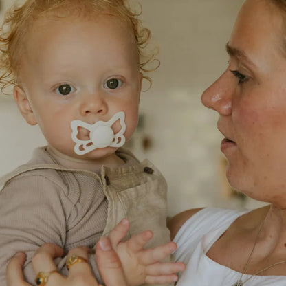 Baby with a Frigg butterfly pacifier held by a woman