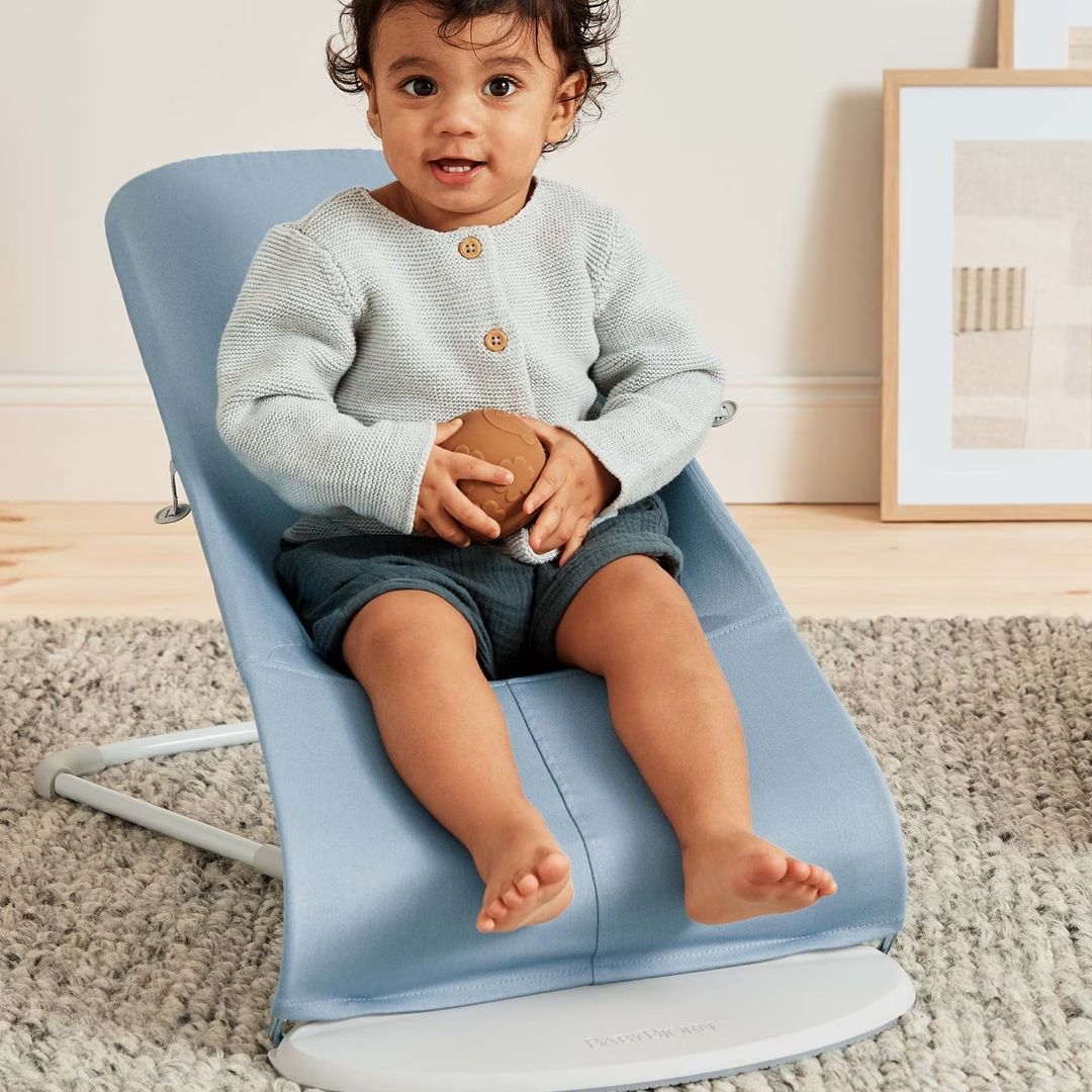  Child sitting on a blue BabyBjorn baby bouncer in a home setting