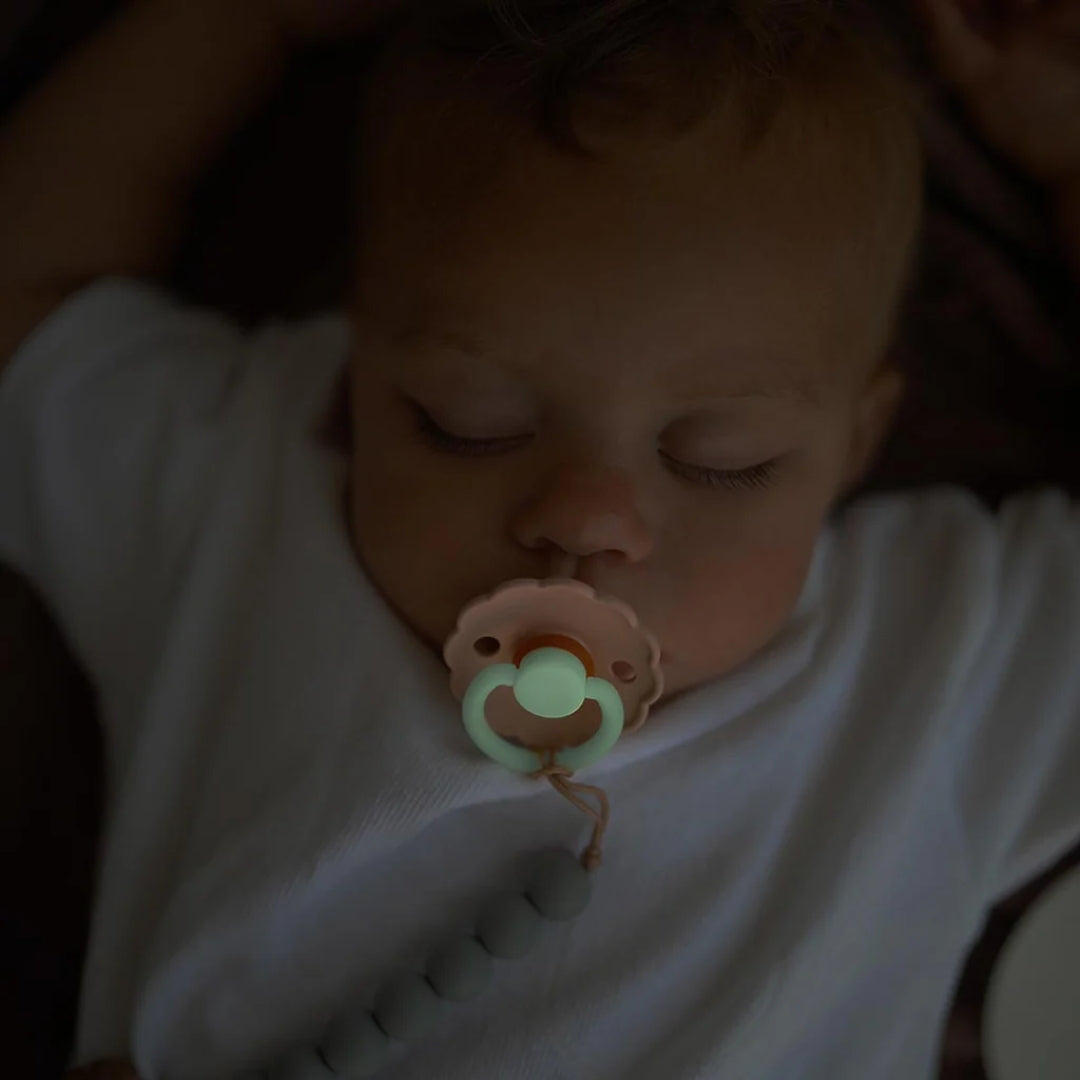 Baby sleeping with a pacifier in a dark setting