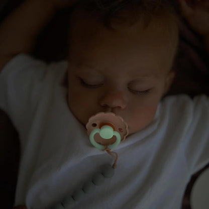 Baby sleeping with a pacifier in a dark setting
