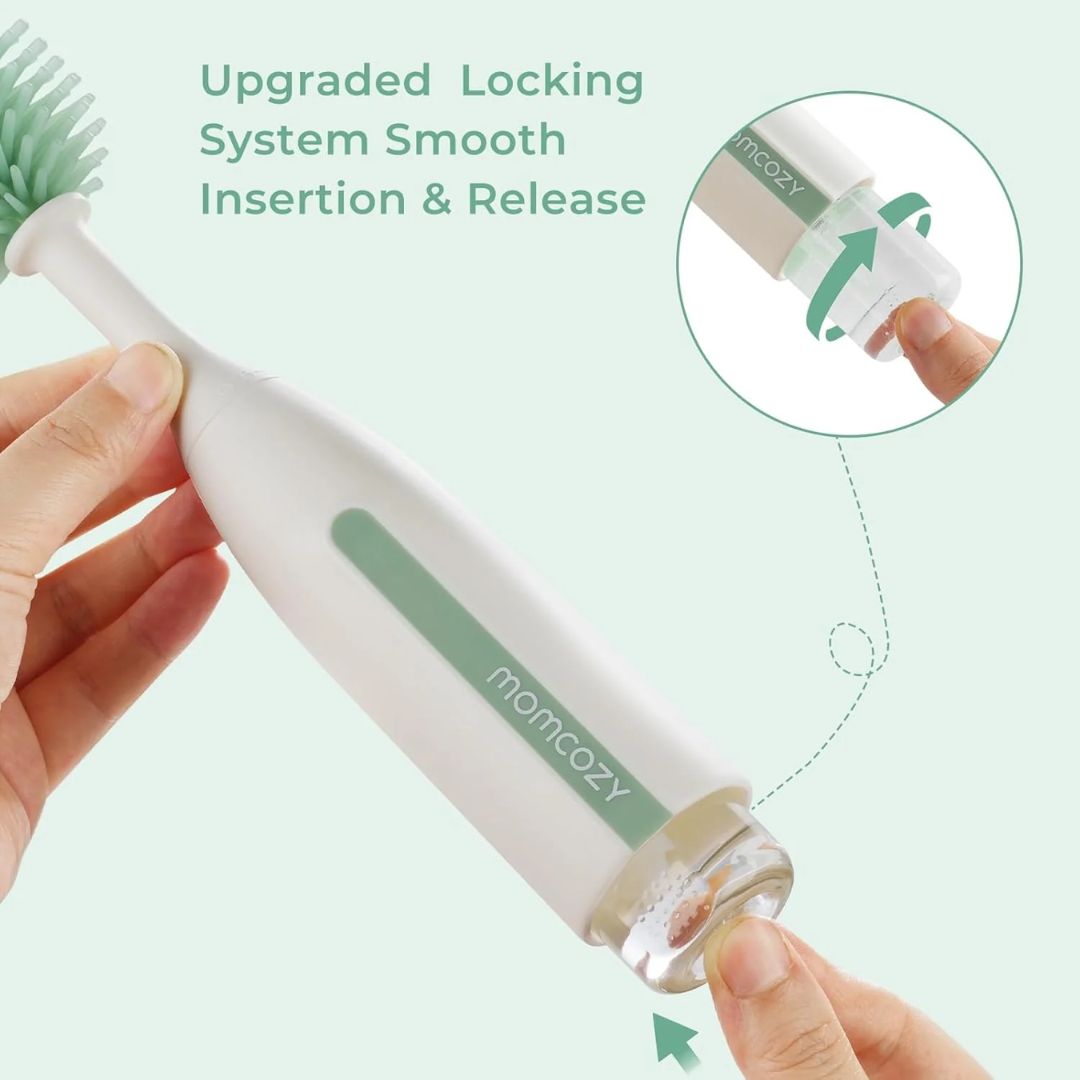 Hand holding a white and green bottle brush with 'momcozy' branding, emphasizing an upgraded locking system.